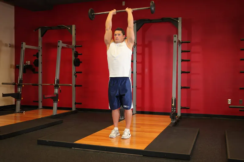Standing Overhead Barbell Triceps Extension: end position